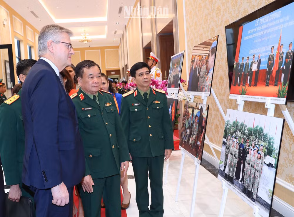 Thượng tướng Hoàng Xuân Chiến, Thứ trưởng Quốc phòng và Phó Tổng Thư ký Liên hợp quốc Jean-Pierre Lacroix cùng các đại biểu xem triển lãm ảnh về phụ nữ với hoạt động gìn giữ hòa bình Liên hợp quốc.