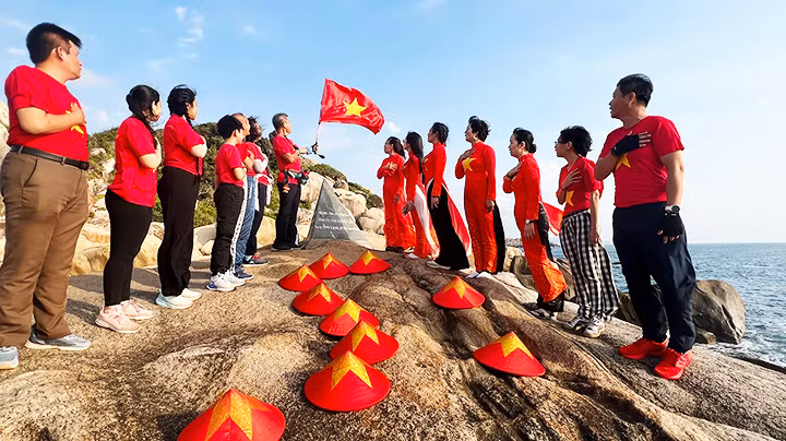 Du khách chào cờ đón ánh bình minh ở Mũi Đôi. Ảnh: THANH AN