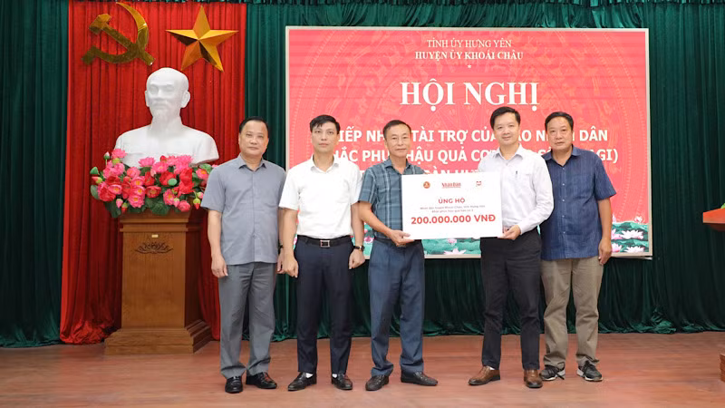 Đại diện Báo Nhân Dân và Công ty cổ phần Văn hóa Đọc và Học Việt Nam trao tặng tiền ủng hộ cho huyện Khoái Châu.