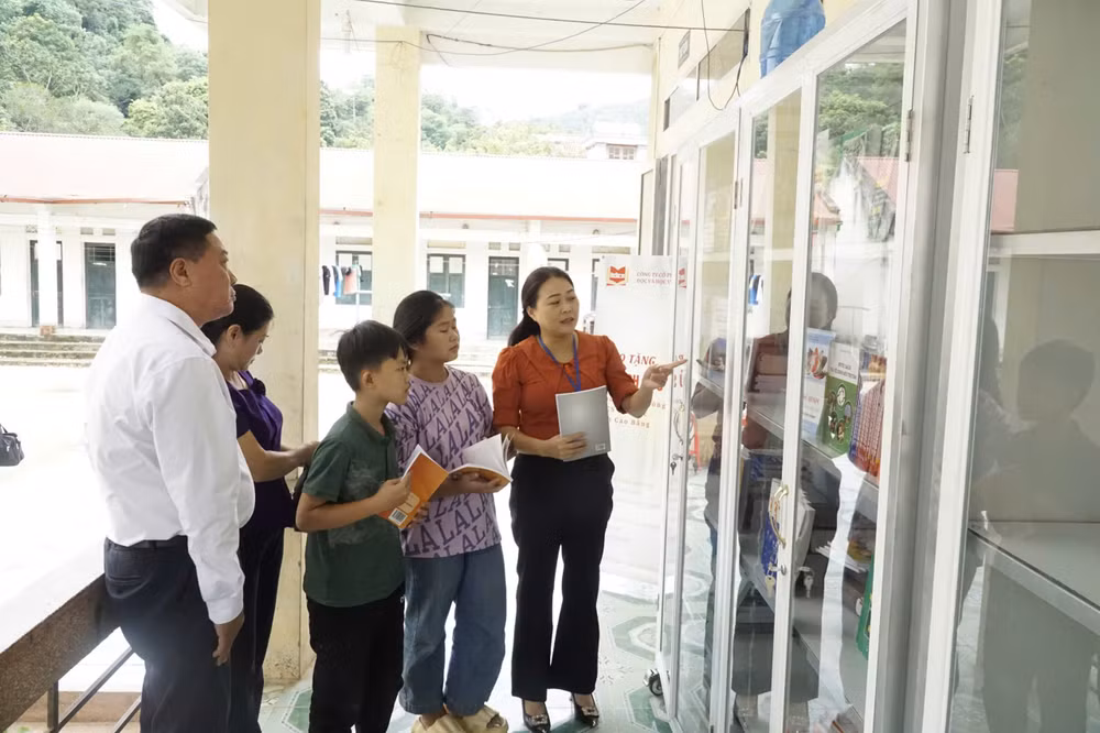 Cô giáo Lục Thị Hạnh (người mặc áo màu cam), Hiệu trưởng Trường phổ thông dân tộc nội trú trung học cơ sở Bảo Lạc giới thiệu tủ sách tới học sinh. (Ảnh: MINH TUẤN)