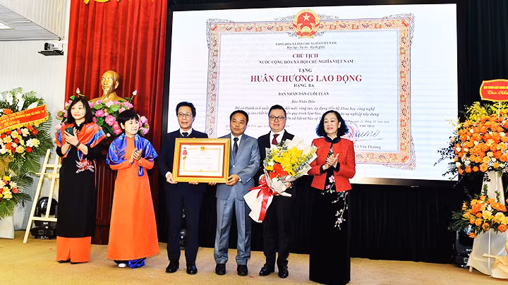 Đồng chí Trương Thị Mai, Ủy viên Bộ Chính trị, Thường trực Ban Bí thư, Trưởng Ban Tổ chức Trung ương Đảng thay mặt lãnh đạo Đảng, Nhà nước trao Huân chương Lao động hạng Ba cho ban Nhân Dân cuối tuần.