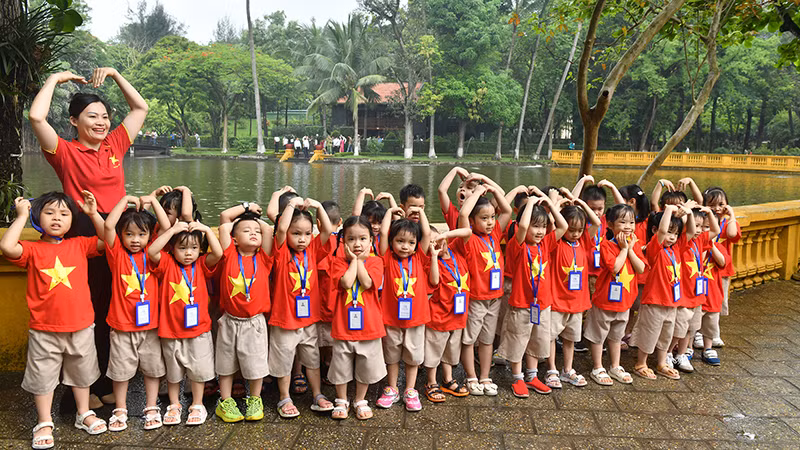 Cô và trò chụp ảnh kỷ niệm bên ao cá Bác Hồ trong Khu Di tích Chủ tịch Hồ Chí Minh tại Phủ Chủ tịch. (Ảnh ÐĂNG KHOA) 