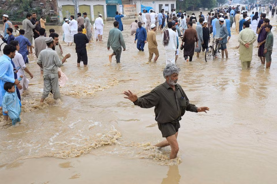 Người dân di chuyển trên con đường bị ngập tại Charsadda. (Ảnh: Reuters)