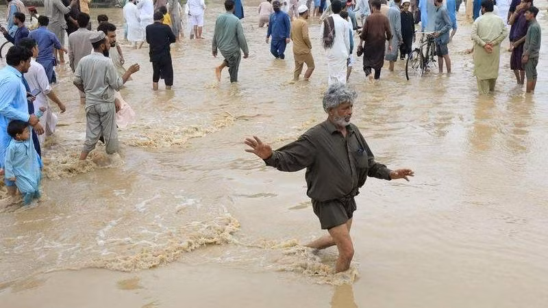 Người dân di chuyển trên con đường bị ngập tại Charsadda, Pakistan. (Ảnh: Reuters)