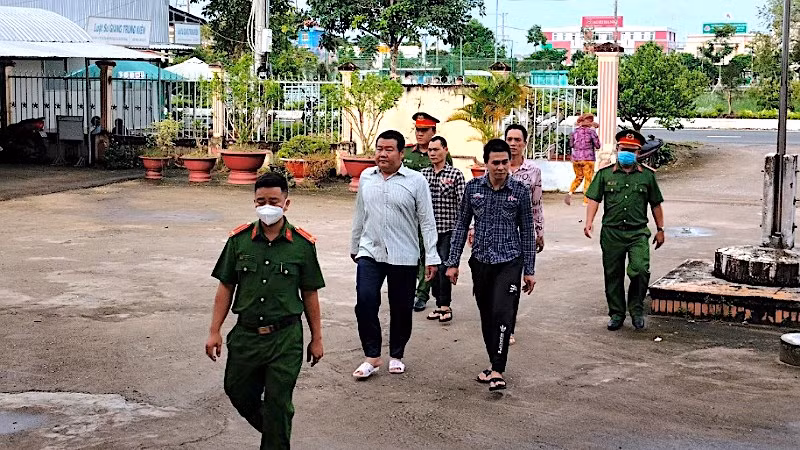 Nhóm bị can hành hạ người khác bị lực lượng Công an áp giải để đưa ra xét xử trước tòa. 
