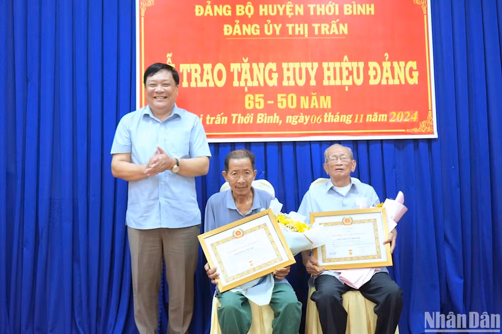 Phó Bí thư Thường trực Tỉnh ủy Cà Mau Phạm Thành Ngại (bìa trái) trao Huy hiệu 65 năm tuổi Đảng và 50 năm tuổi Đảng cho đảng viên Huỳnh Văn và đảng viên Trịnh Quang Kế.