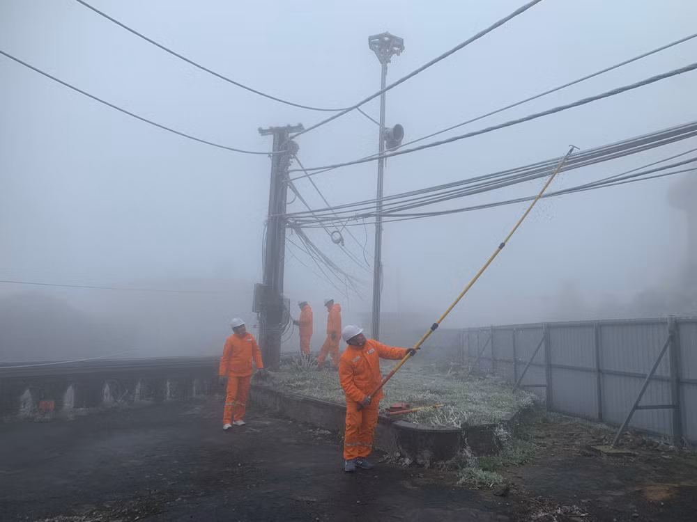 Công nhân Điện lực Lộc Bình gạt các tảng băng dày bám vào đường dây.