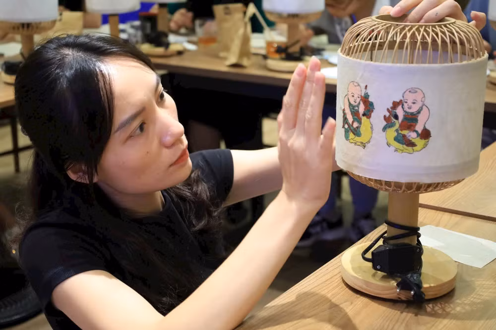Tranh dân gian Đông Hồ được ứng dụng vào sản xuất sản phẩm đèn bàn. (Ảnh Dự án "Màu dân tộc". Tranh dân gian Đông Hồ được ứng dụng vào sản xuất sản phẩm đèn bàn. (Ảnh Dự án "Màu dân tộc".