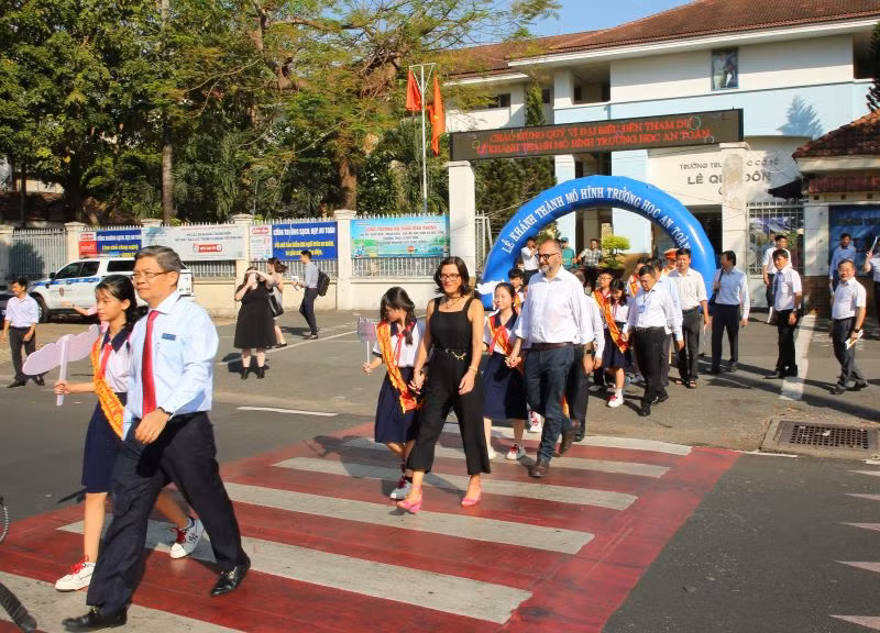 Các đại biểu dẫn học sinh qua đường.