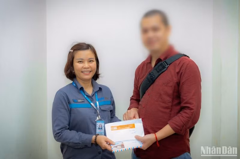 Chị Tươi trao lại chiếc túi chứa 4.300 USD cho anh V.Q.Đ. trong niềm vui sướng của anh.
