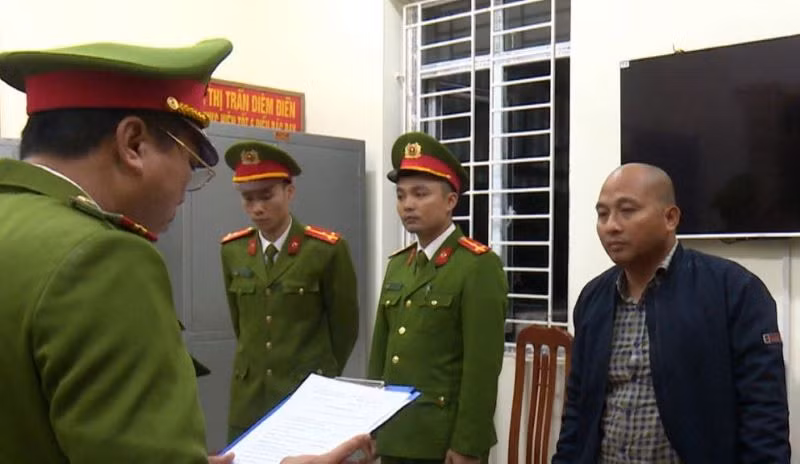 Nguyễn Văn Đoàn (bên phải) nghe Cơ quan Cảnh sát điều tra đọc các Quyết định khởi tố vụ án, khởi tố bị can và Lệnh bắt bị can để tạm giam. (Ảnh: Công an cung cấp)