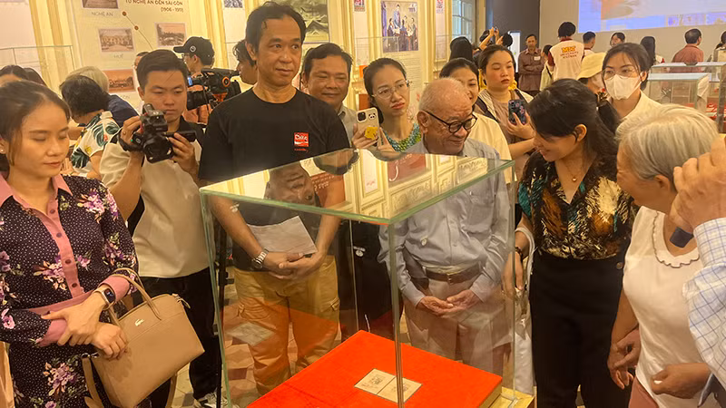 Khách tham quan thưởng lãm block tem kỷ niệm 70 năm Ngày sinh Chủ tịch Hồ Chí Minh có chữ ký của Người. (Ảnh: M.H)