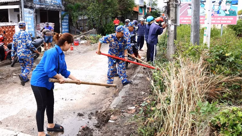 Cán bộ, đoàn viên thanh niên các đơn vị Hải quân và thanh niên địa phương dọn vệ sinh các tuyến đường giao thông ở xã Hàng Vịnh, huyện Năm Căn, tỉnh Cà Mau.