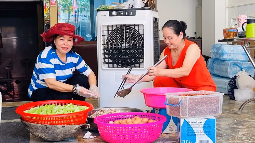Bà Lý (bìa trái) tham gia chia khẩu phần thức ăn phục vụ bữa trưa 18/9. (Ảnh: THANH SƠN)