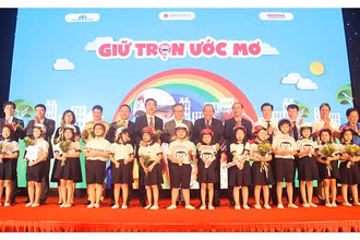 Phó Thủ tướng Trương Hòa Bình và các đại biểu trao tượng trưng mũ bảo hiểm đạt chuẩn cho các học sinh lớp một tại lễ công bố chương trình “Giữ trọn ước mơ” ngày 3-7.
