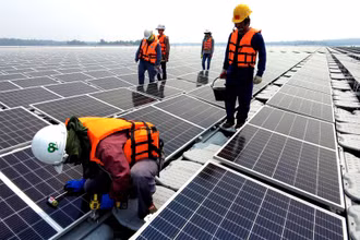 Công nhân lắp đặt các tấm pin mặt trời tại trang trại điện nổi. (Ảnh: Reuters)