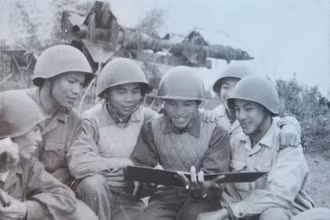 Ông Nguyễn Quang Hùng (ngồi giữa, tay cầm sổ rút kinh nghiệm chiến đấu) khi còn là sĩ quan điều khiển cùng với kíp chiến đấu Tiểu đoàn 62 tại trận địa Cổ Nhuế, Hà Nội, năm 1967. (Ảnh: nhân vật cung cấp)