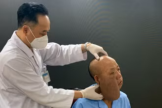 PGS, TS Trần Cao Bính, Giám đốc Bệnh viện Răng Hàm mặt Trung ương thăm khám cho bệnh nhân trước khi phẫu thuật.