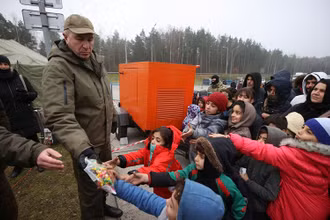 Những người di cư nhận đồ cứu trợ nhân đạo tại khu vực biên giới Belarus-Ba Lan, tháng 11/2021. (Ảnh: Reuters)
