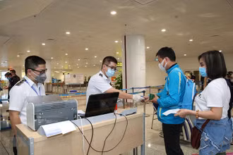 Nhân viên y tế kiểm tra phiếu khai báo y tế của hành khách trước khi làm thủ tục nhập cảnh tại cửa khẩu Sân bay quốc tế Nội Bài (Ảnh: TTXVN)