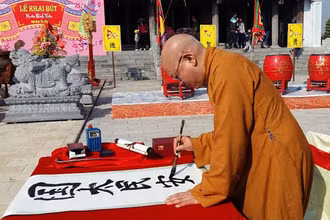 Thượng tọa Thích Quang Tùng khai bút với bức thư pháp bốn chữ “Quốc thái, dân an”. Ảnh chụp Xuân Bính Thân 2016 của NGÔ QUANG DŨNG