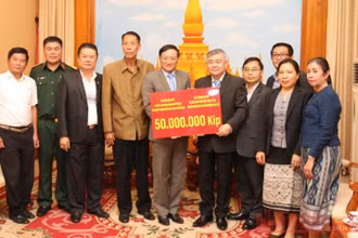 Đại sứ Việt Nam tại Lào Nguyễn Bá Hùng (thứ 5 từ trái qua) trao số tiền ủng hộ Lào, chiều 26-10.