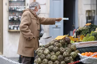 Một người đàn ông đi mua hàng tại Italia. Ảnh: REUTERS