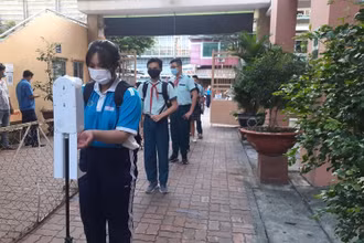 Học sinh tại Thành phố Hồ Chí Minh kiểm tra thân nhiệt, sát khuẩn tay trước khi vào lớp học.