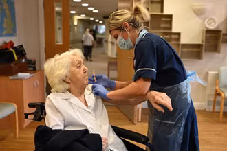 Nhân viên y tế tiêm vaccine phòng COVID-19 cho một cụ bà ở Wigan (Anh). (Ảnh: AFP/TTXVN)