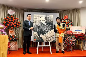Đồng chí Lê Quốc Minh thay mặt Hội Nhà báo Việt Nam nhận bức vẽ “Bác Hồ đọc Báo Nhân Dân” do tác giả Huỳnh Dũng Nhân trao tặng.