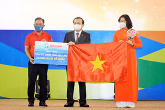 Bà Phan Thị Thắng, Phó Chủ tịch UBND TP Hồ Chí Minh và ông Bùi Thanh Liêm (bìa trái), Phó Tổng Biên tập Báo Người Lao Động, trao cờ Tổ quốc và bảng tượng trưng 20.000 lá cờ cho ông Lê Tấn Cận, Phó Chủ tịch UBND tỉnh Bạc Liêu.