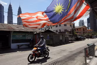Người đàn ông đeo khẩu trang khi tham gia giao thông tại Kuala Lumpur trong thời gian thành phố này bị phong tỏa để chống Covid-19, ngày 2/2/2021. (Ảnh: Reuters)