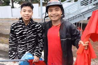 Hai cha con anh Nam bán cờ với hy vọng có thêm tiền để mua vé vào sân. (ẢNH: Sơn Bách)