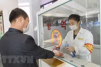Khử khuẩn tay, đo thân nhiệt, nhằm ngăn chặn sự lây lan của dịch Covid-19 trước khi vào trung tâm thương mại ở Bình Nhưỡng, Triều Tiên. (Ảnh: AFP/TTXVN)