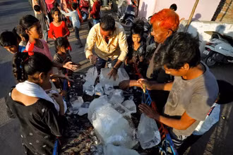 Người dân ở thành phố Ahmedabad, bang Gujarat, Ấn Độ vây quanh 1 xe chở đá để giảm nhiệt giữa nắng nóng gay gắt, ngày 28/4/2022. (Ảnh: Reuters)