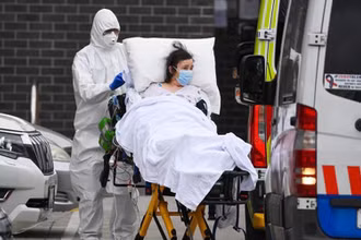 Nhân viên y tế chuyển bệnh nhân Covid-19 lên xe cứu thương tại thành phố Melbourne, Australia. (Ảnh: AFP/TTXVN)