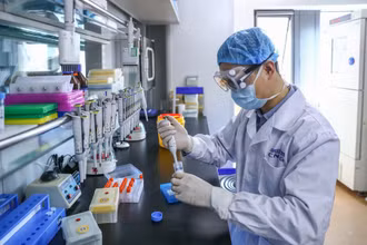 Một nhân viên kiểm tra mẫu vaccine Covid-19 tại nhà máy sản xuất vaccine của Tập đoàn Dược phẩm Quốc gia Trung Quốc (Sinopharm) ở Bắc Kinh, Trung Quốc ngày 11-4-2020. Ảnh: Tân Hoa Xã.