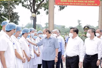 Chủ tịch nước Nguyễn Xuân Phúc thăm hỏi nhân viên y tế làm việc tại cơ sở thu dung, điều trị bệnh nhân Covid-19 của Bệnh viện đa khoa Hà Đông, tại phường Hoàng Liệt, quận Hoàng Mai. (Ảnh: TTXVN)