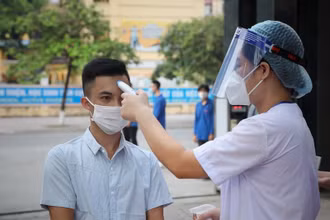 Kiểm tra thân nhiệt cho thí sinh trước khi vào điểm thi tại Hội đồng thi Bắc Giang. Ảnh: DANH LAM/TTXVN