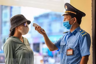 Nhân viên an ninh nhà ga Hà Nội kiểm tra thân nhiệt cho khách đến mua vé tàu sáng 12/10. (Ảnh: Thành Đạt/TTXVN)