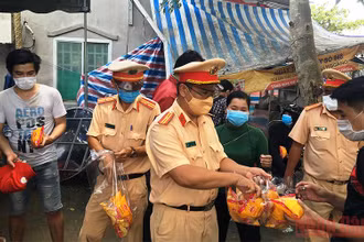 Lực lượng công an phát bánh mì, nước uống cho bà con trong lúc chờ xe đến đón về địa phương cách ly theo quy định.