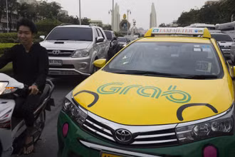 Một chiếc xe taxi dán biểu tượng ứng dụng gọi xe trực tuyến Grab lưu thông tại Thái Lan (Ảnh Bloomberg)