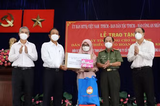 Nguyên Phó Thủ tướng Thường trực Chính phủ Trương Hòa Bình (thứ 2 từ trái qua) và đại diện các đơn vị trao tặng thiết bị học tập trực tuyến cho các em học sinh dân tộc Chăm tại quận 8.
