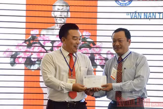 Chủ tịch Hội Nhà báo tỉnh Khánh Hòa Đoàn Minh Long (trái) trao khoản tiền 10 triệu đồng do Hội thảo quyên góp cứu trợ đồng bào miền trung bị bão lụt.