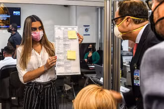 Các nhân viên bầu cử kiểm tra một lá phiếu được bầu qua đường bưu điện tại Miami, ngày 3-11-2020. (Ảnh: Getty Images)