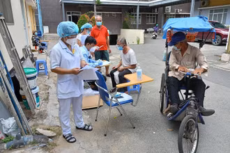 Nhân viên y tế kiểm tra kỹ thông tin trước bên ngoài phòng tiêm chủng.