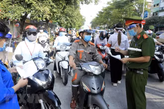 Lực lượng chức năng kiểm tra giấy tờ tùy thân và xác nhận đi làm, ra ngoài của cơ quan với người dân lưu thông trên đường Đào Tấn, Hà Nội, sáng 28/7.