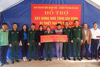 Sĩ quan dự bị Trần Hữu Diệu (áo xám trong ảnh) nhận nguồn hỗ trợ, động viên để xây dựng “Ngôi nhà 100 đồng” từ đại diện Ban Thanh niên quân đội ngay trên nền căn nhà cấp 4 vừa bị lũ cuốn trôi.