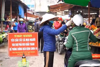 Kiểm tra thân nhiệt cho người dân tại chợ trung tâm TP Cẩm Phả (Quảng Ninh).