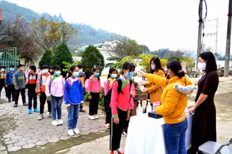 Học sinh Trường tiểu học Quang Kim (Bát Xát- Lào Cai) đeo khẩu trang, rhực hiện đo thân nhiệt và sát khuẩn tay trước khi vào lớp học. 
